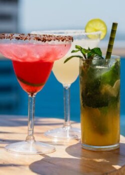 Glass of spritz aperol with orange slice against poolside at resort hotel during vacation. Elegant goblet of sparkling wine and orange juice on background of blue water outdoor. Relaxation and travel.